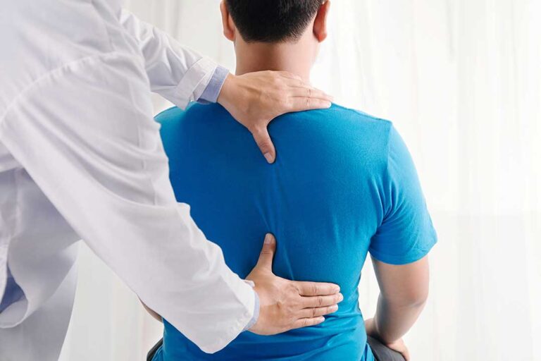An older adult stretching their back with gentle guidance from a healthcare professional.