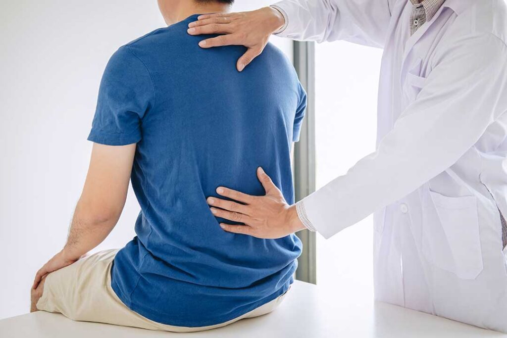 Person discussing a back pain treatment plan with a chiropractor in a bright clinical room.